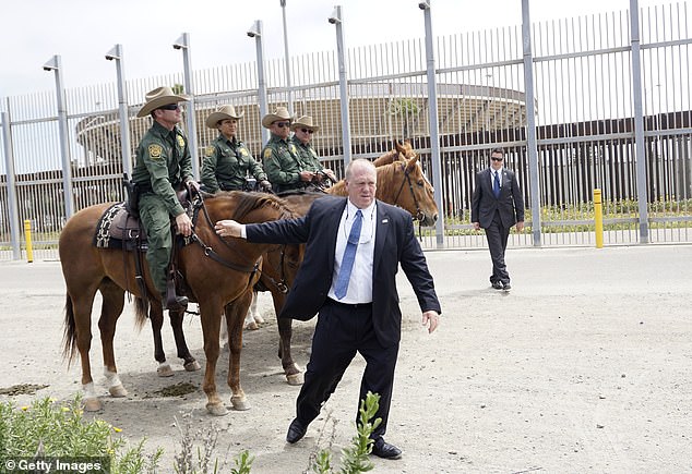 Tom Homan berbicara dengan agen Patroli Perbatasan di dekat tembok perbatasan selatan di San Ysidro, California pada 7 Mei 2018