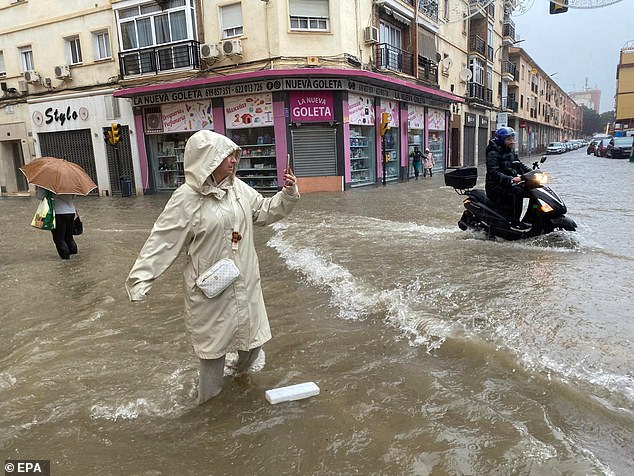 Seorang wanita mengambil foto jalan yang banjir di Malaga, Andalusia, Spanyol, 13 November 2024